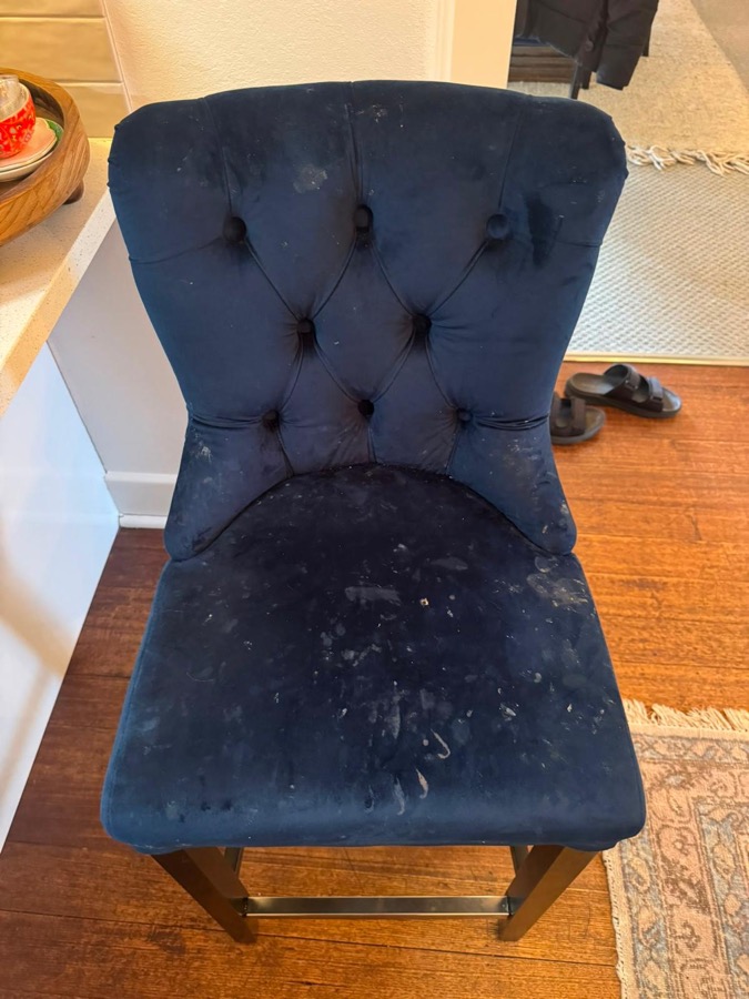 Navy velvet chair covered in paint specks before cleaning