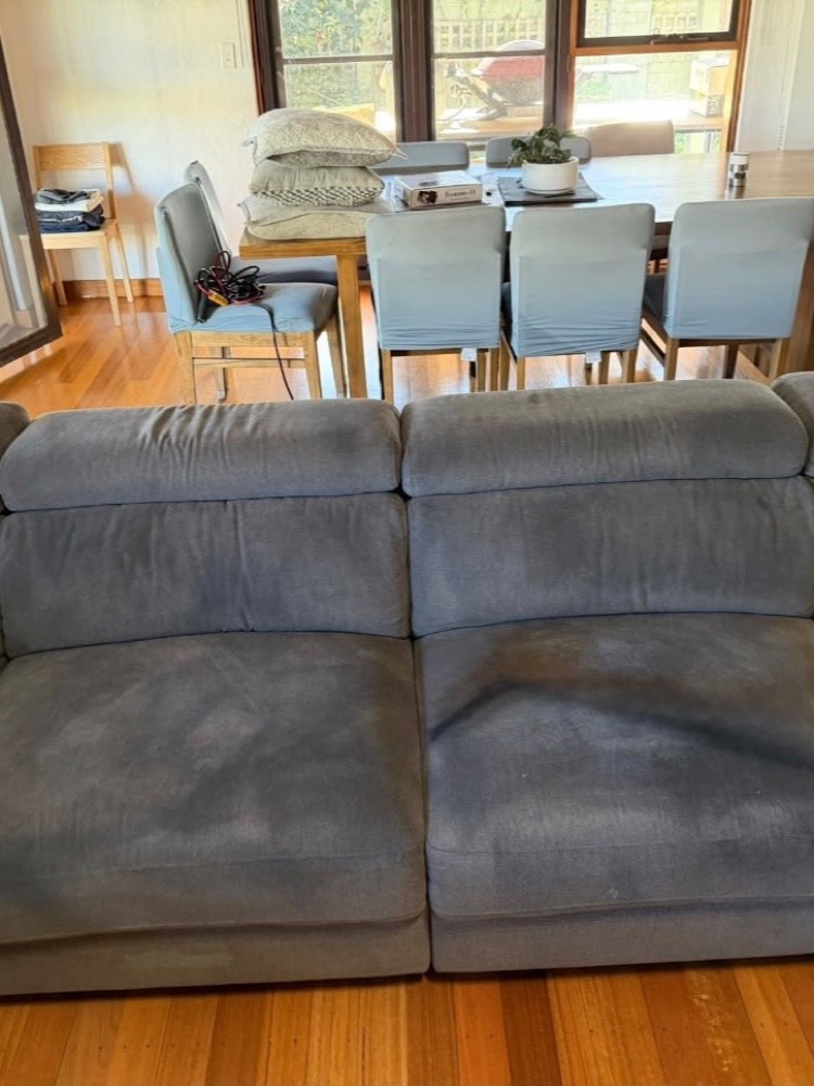 Grey modular sectional with deep body-oil stains before upholstery cleaning