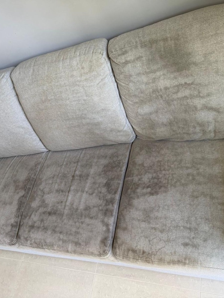 Grey three-seater sofa with heavily soiled seat cushions before cleaning